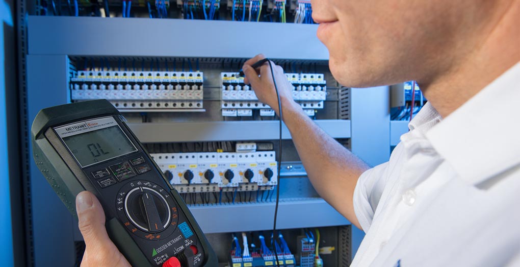 HPS - A worker with a meter on the control cabinet